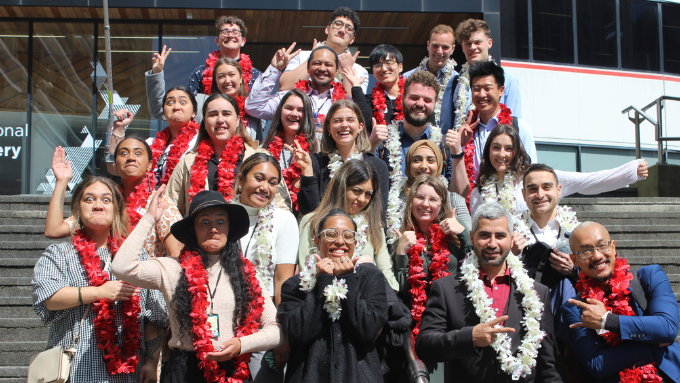 classroom group photo standing on a group of stairs with all of them wearing a lei