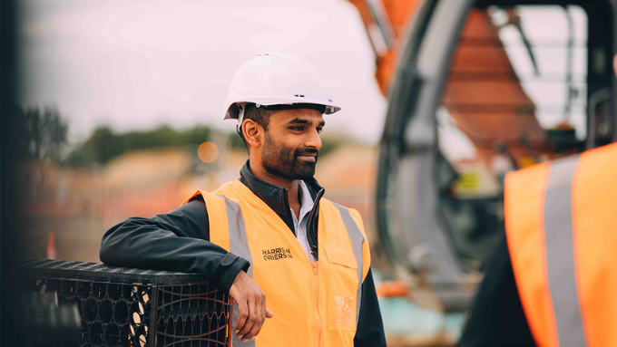 blue collar worker out doors with his PPE on looking away from the camera