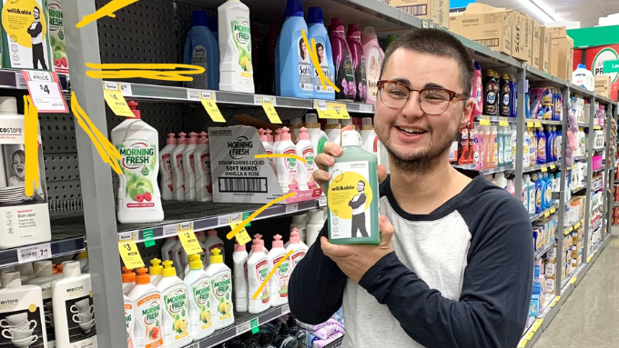 male in a supermarket smiling at the camera with a dishwashing liquid product