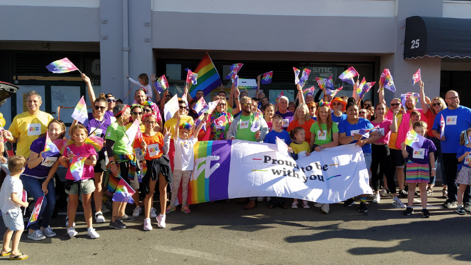 Accident Compensation Corporation group photo outdoors everyone excited and holding rainbow flags