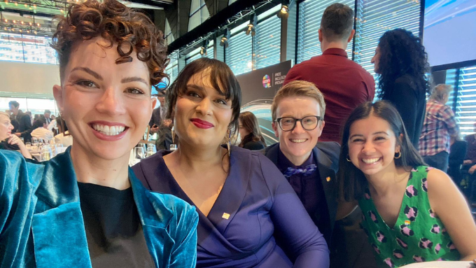 four individuals seated at an event taking a selfie