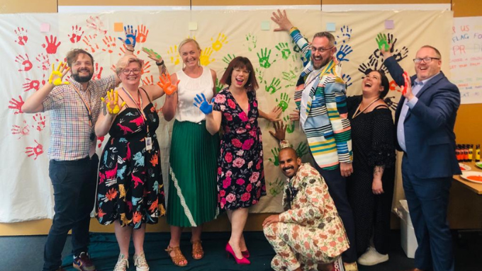 group of people placing their painted hands onto a big sheet of paper