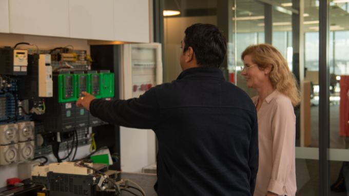 male showing a woman how to use some equipment. Both have their backs to the camera