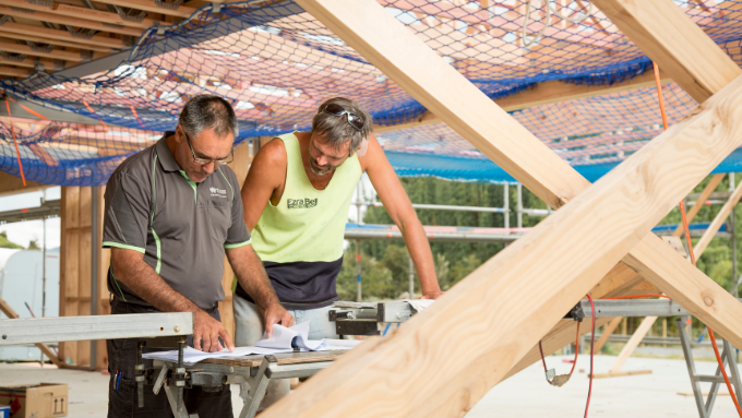two trades men looking at plans for building a house