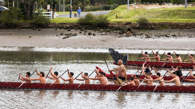 photo groups of men rowing a waka in a lake