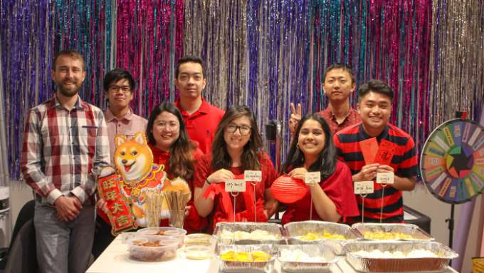 group photo seated at a table with food indoors all smiling at the camera 
