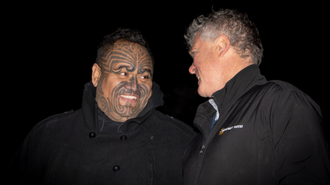 two males one with a tamoko both looking at each other talking