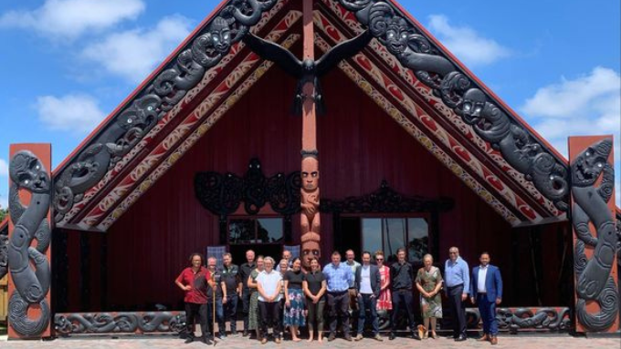 Kiwibank group photo all facing the camera outdoors in front of a marae
