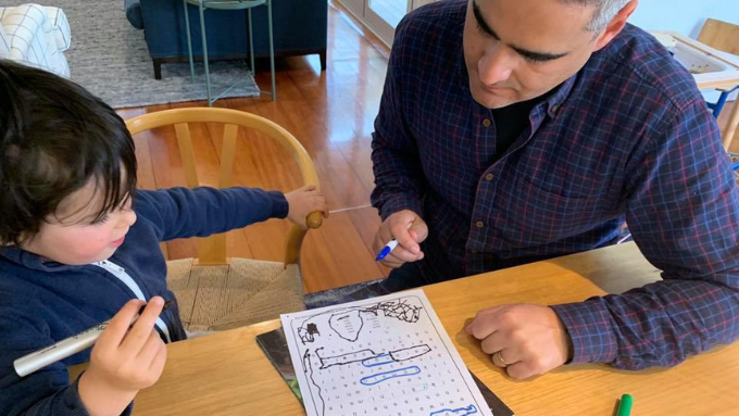 male with a younger child doing a wordfind game