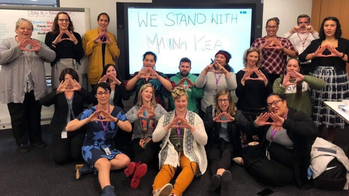 Southern Cross Health Society group photo everyone making a love heart shape and looking at the camera indoors