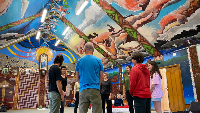 people indoors looking up at a colourful roof with their backs to the camera
