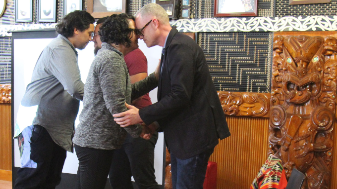 four people greeting one another with a hongi (traditional māori greeting) on a marae