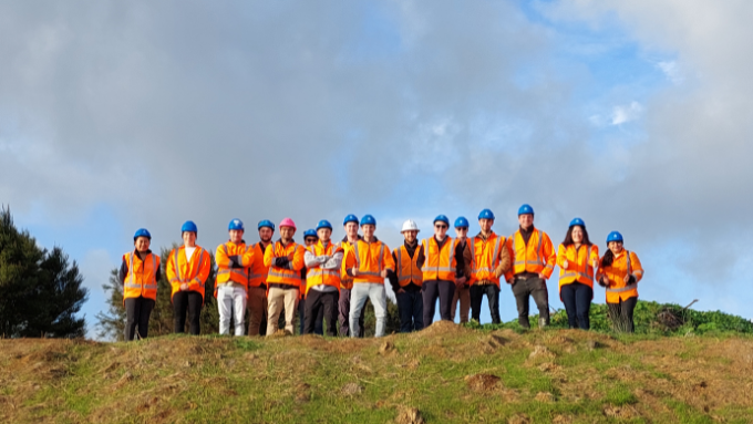 A group of HEB Construction workers standing on top of a hill all looking down at the photographer wearing Hi Vis jackets and hard hats