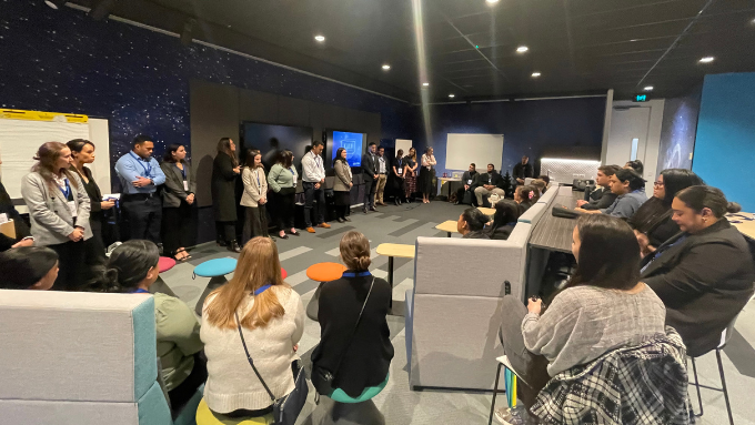 KPMG staff sitting in a group listening to a row of speakers standing facing them in a large meeting room KPMG staff sitting in a group listening to a row of speakers standing facing them in a large meeting room