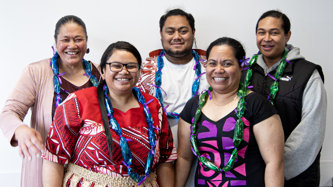 A group of five Samoan people smiling at the camera in traditional wear