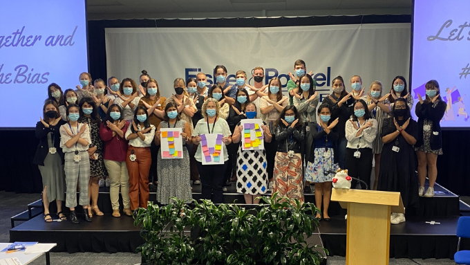 A group of Fisher & Paykel Healthcare staff on stage wearing masks and making an X shape with their hands