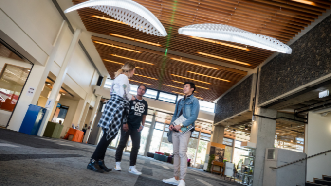 Three Otago Polytechnic students talking amongst each other indoors 