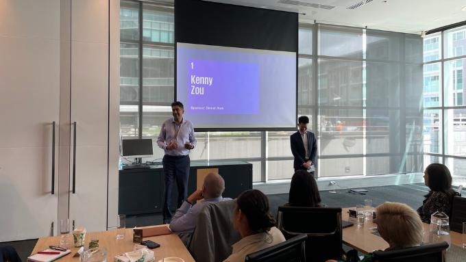 two KPMG staff standing at the front of a conference room presenting to a group of people two KPMG staff standing at the front of a conference room presenting to a group of people
