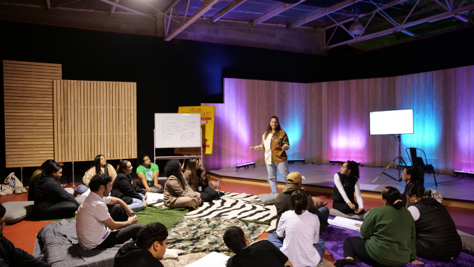 Woman standing on animal print rug talking to an audience seated on the floor Woman standing on animal print rug talking to an audience seated on the floor