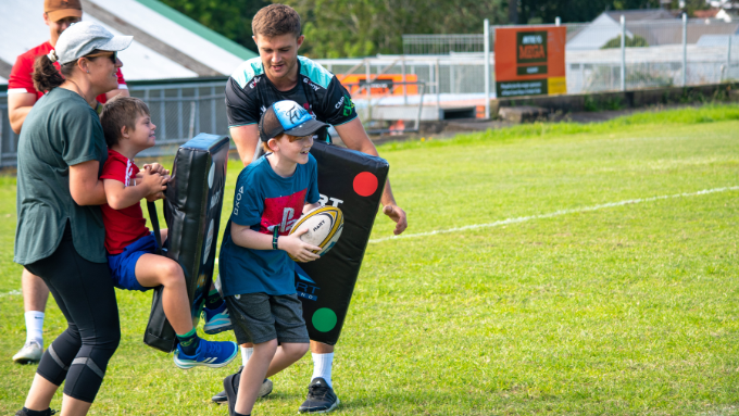 kids learning how to play rugby on a field with adults