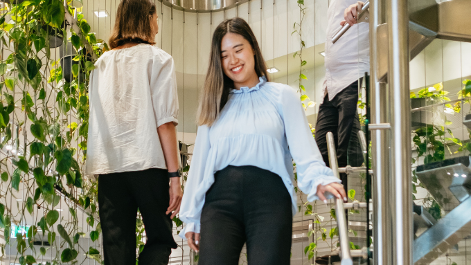 a woman walking down some stairs smiling and one walking up the stairs with her back to the camera