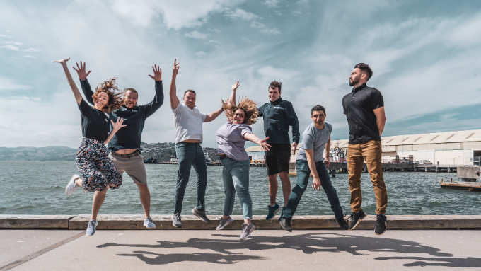 seven people jumping in the air on a wharf with the sea and cloudy sky behind them seven people jumping in the air on a wharf with the sea and cloudy sky behind them