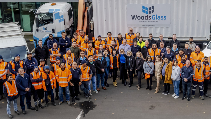 Woods Glass team in front of a branded wood glass container all looking up at the camera all smiling Woods Glass team in front of a branded wood glass container all looking up at the camera all smiling