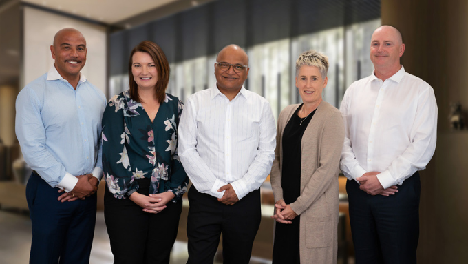 Five Hind Management senior staff standing together smiling at the camera for a group photo Five Hind Management senior staff standing together smiling at the camera for a group photo
