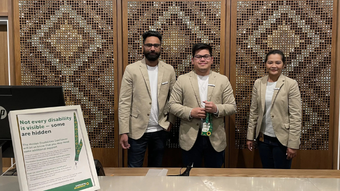Three Hind Management staff standing at the hotel reception with decorative panels behind them