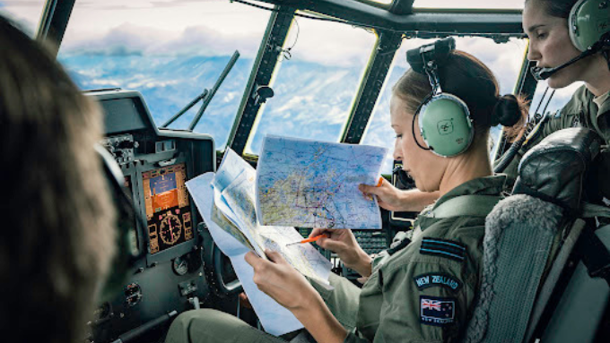 New Zealand Defence Force women inside the cab of a helicopter piloting it 