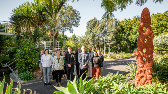 Plant and Food Research group facing the camera smiling outdoors in front of a māori carving statue
