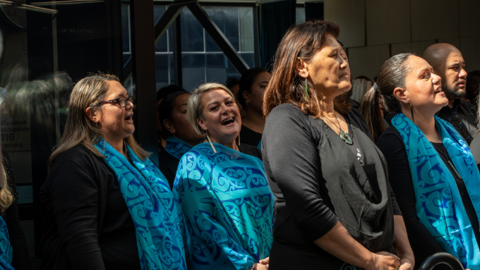 Auckland City Mission wahine singing a waita wearing colourful traditional māori pattern scarves