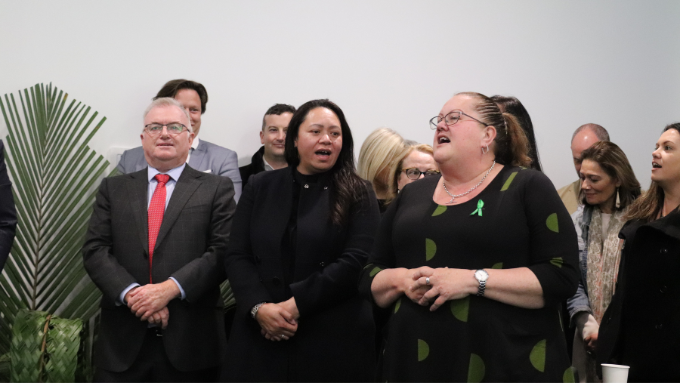 a group of people standing together singing indoors a group of people standing together singing indoors