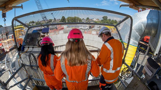 three jacobs construction workers operating a crane