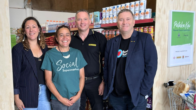 Four people standing in front of supermarket shelf smiling at the camera Four people standing in front of supermarket shelf smiling at the camera