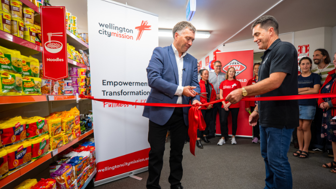 Two men cutting a ribbon at a social supermarket opening