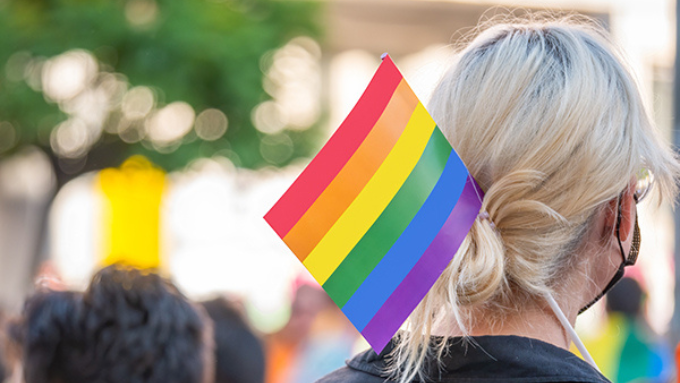 The back of a person at a pride rally with pride flag at a rally The back of a person at a pride rally with pride flag at a rally