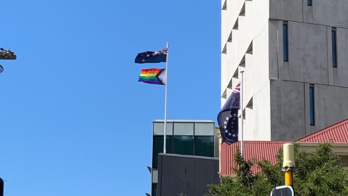 New Zealand flag and pride flag blowing in the wind together above auckland city 