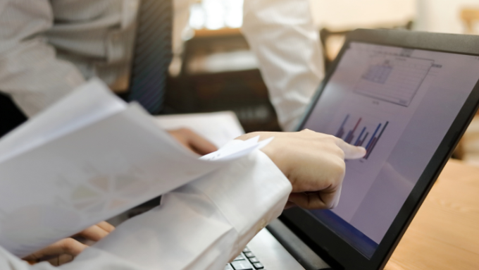 People around a laptop discussing numbers and charts on the screen