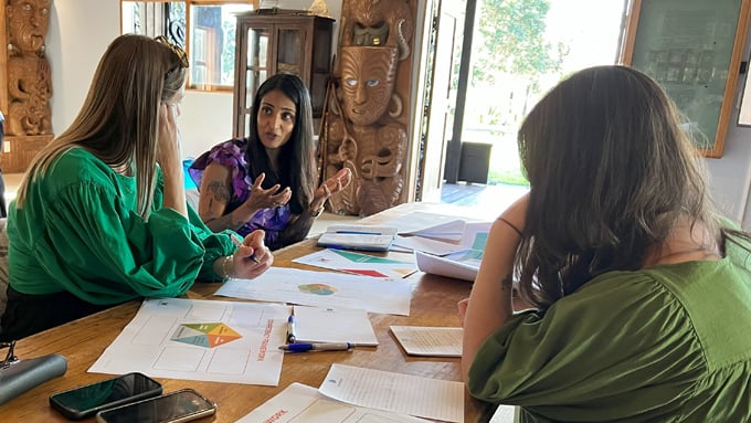 Three women sitting around table on a marae talking Three women sitting around table on a marae talking