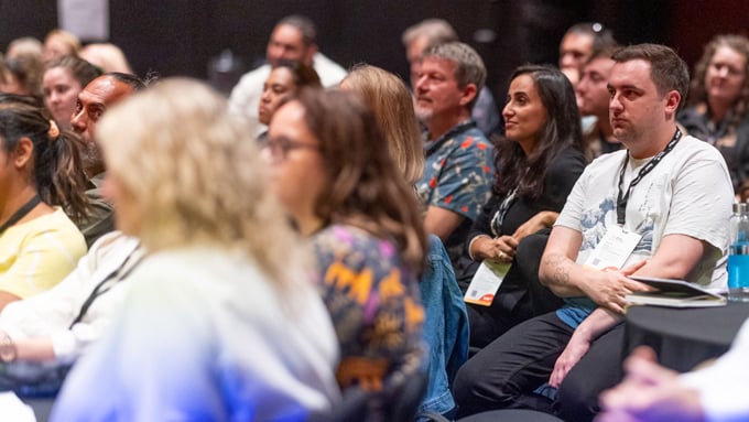 A group of people in the audience at a conference A group of people in the audience at a conference