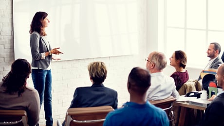 Woman facilitating workshop standing in front of group Woman facilitating workshop standing in front of group
