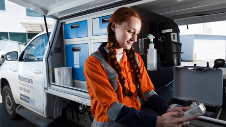Woman working for watercare getting equipment from the back of a company vehicle Woman working for watercare getting equipment from the back of a company vehicle